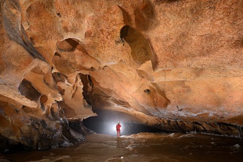 Cueva Fresca (Cantabrie, Espagne) - Galerie au plafond orange avec personnage en fond dans halo(SP-26-0923)